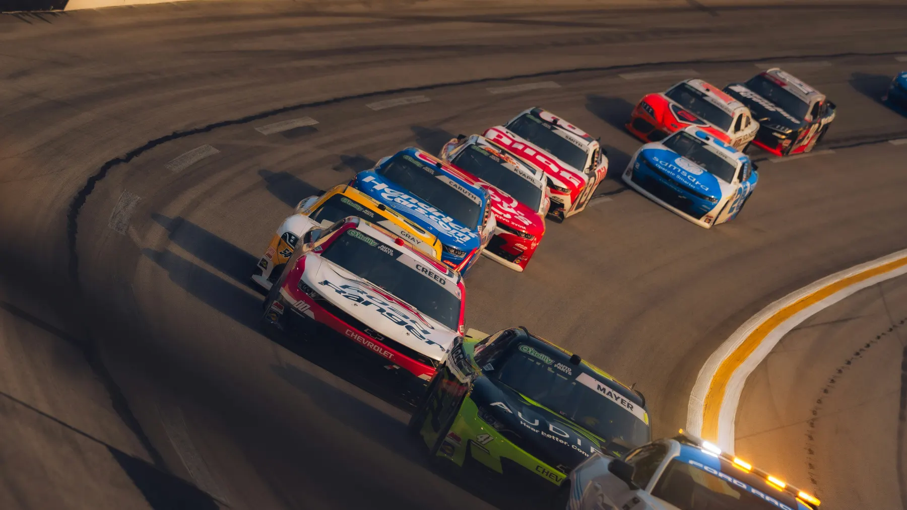 Race cars in a banked turn at sunset